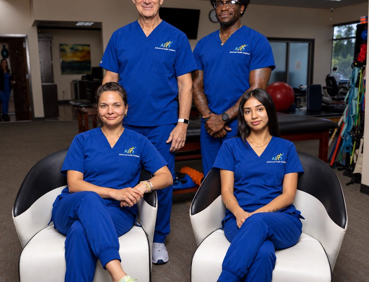 Advanced Health Solutions: staff in blue scrubs seated and standing in the physical therapy room
