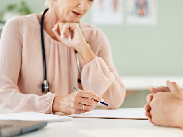 Advanced Health Solutions: doctor and patient writing on paperwork at a clinic desk