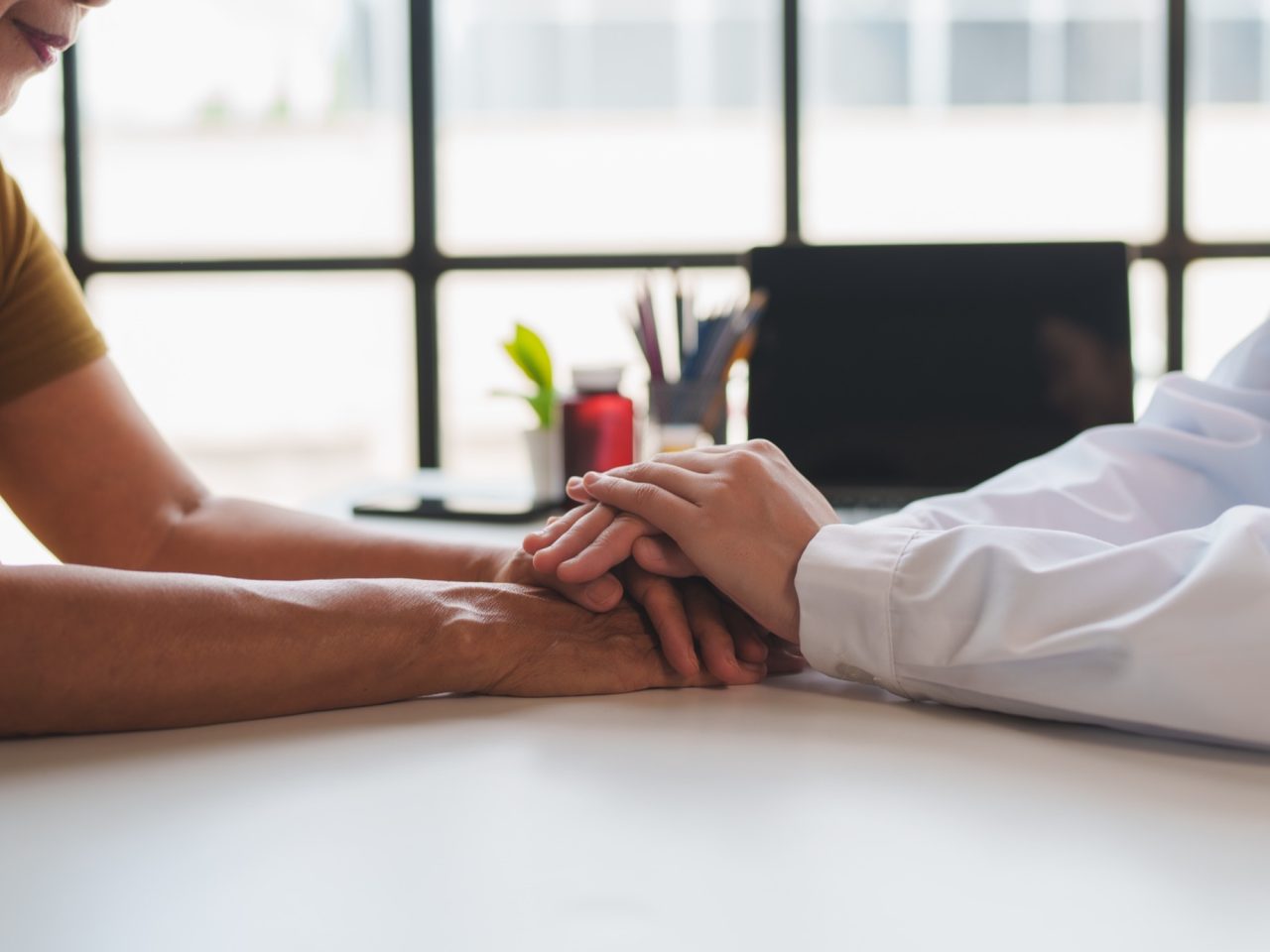 Advanced Health Solutions: doctor holding a senior patient's hands during a consultation