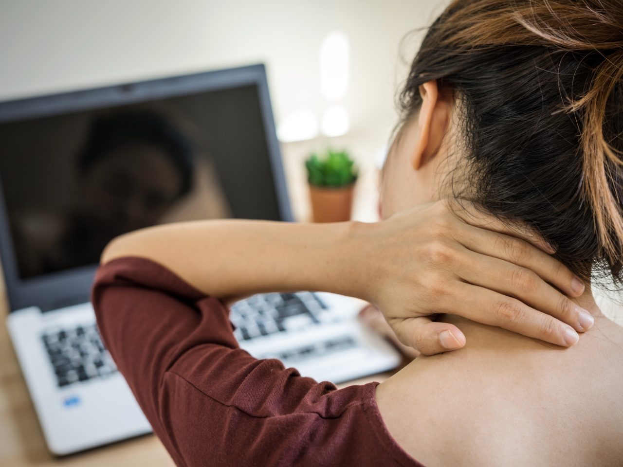 Advanced Health Solutions: young woman working at home with neck pain