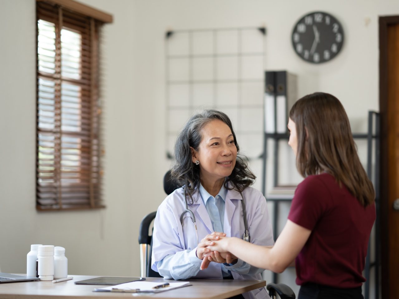 Advanced Health Solutions: senior medical professional supporting a young female patient at an appointment